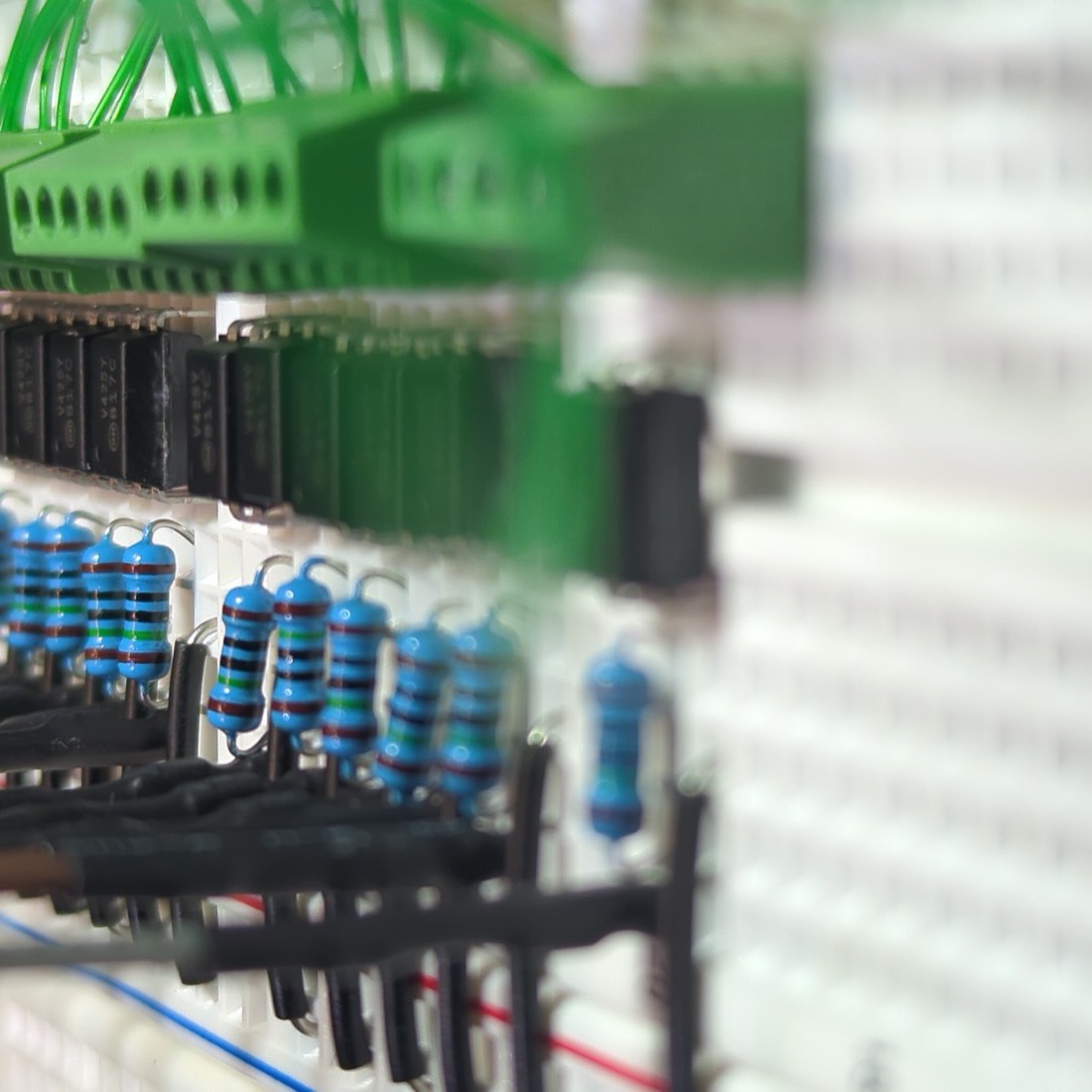 Breadboard with a row of optocouplers and resistors wired to screw terminals