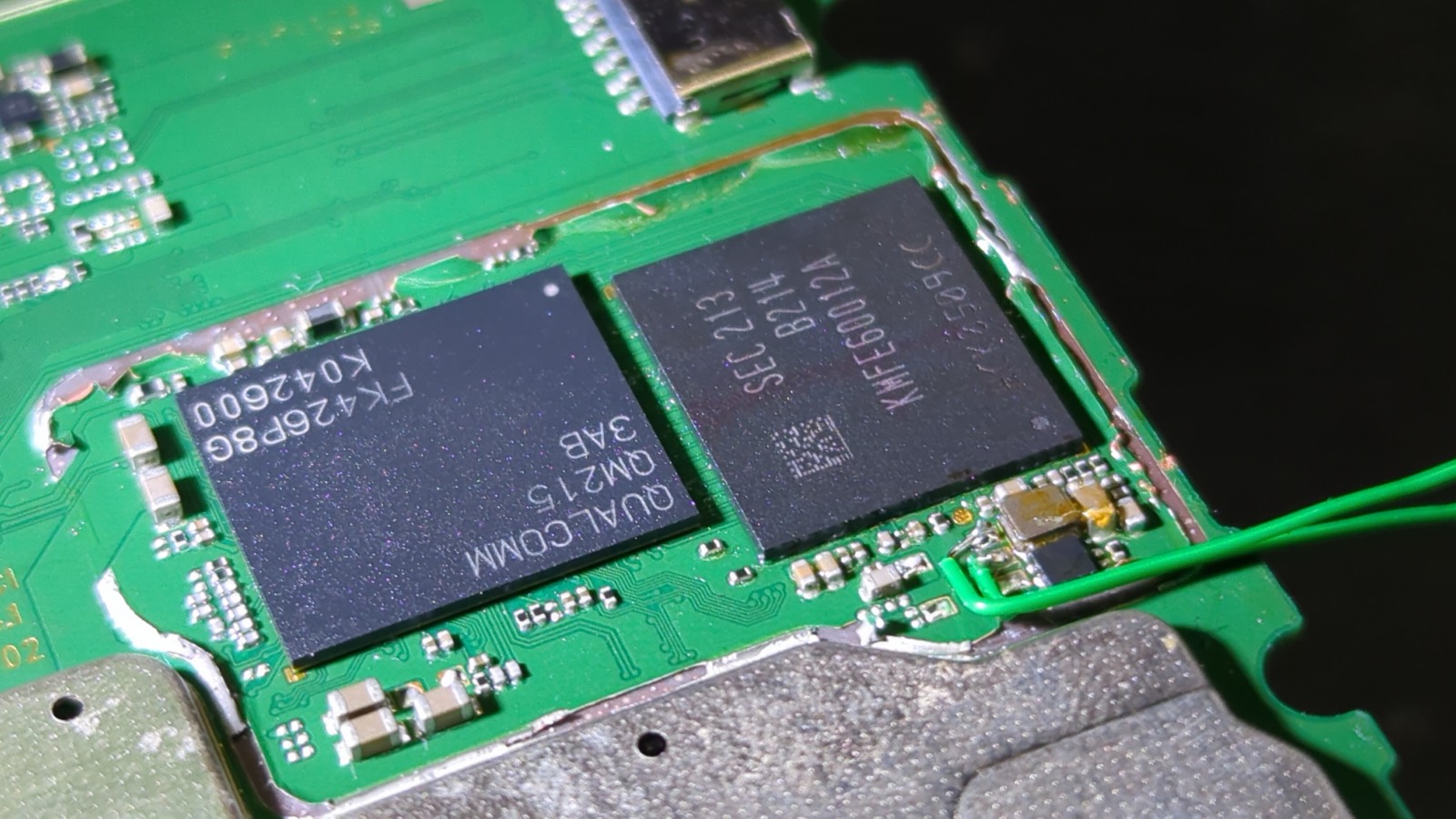 Device mainboard with the RF shield removed, exposing the Qualcomm SoC and Samsung eMMC, with wires attached to the eMMC voltage line