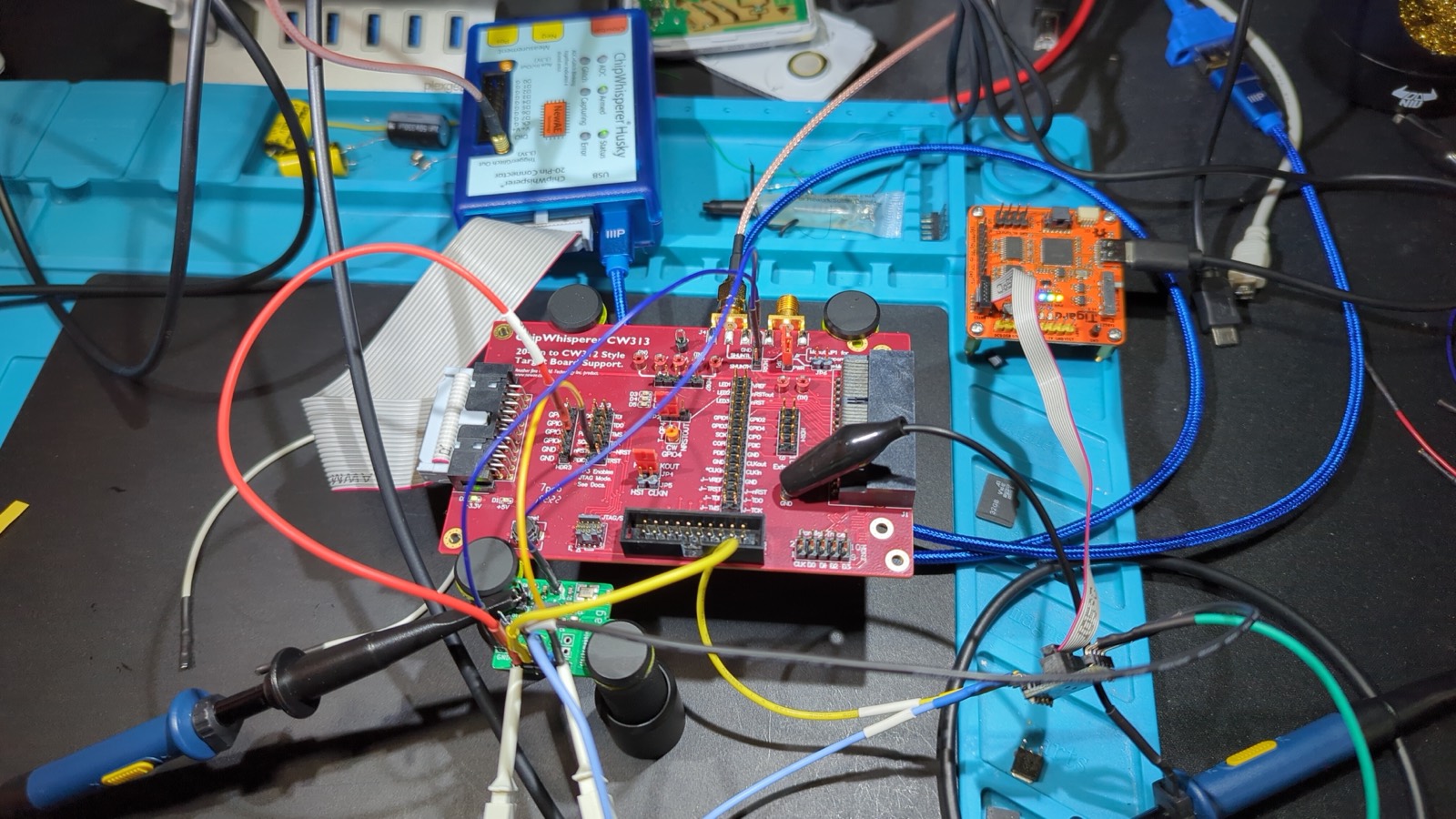 Fault-injection bench: ChipWhisperer Husky wired to a target board, with logic and oscilloscope probes attached