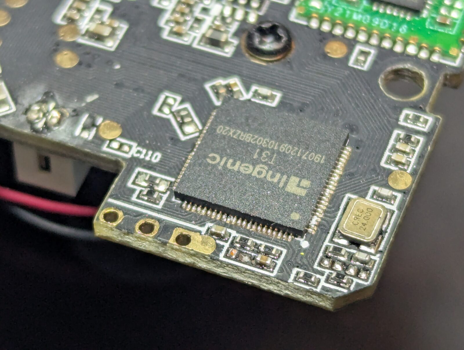 Close-up of the camera mainboard showing a square QFN chip silkscreened Ingenic T31, with a row of gold test pads along the bottom edge.